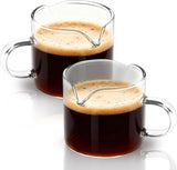 Two clear glass pitchers with handles and spouts for coffee or milk