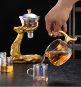 RORA gold deer tea set with a hand pouring tea into a glass cup, black background