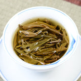 Steeped Pu'er tea leaves in a white ceramic cup on a saucer, top view