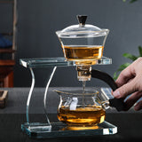 RORA gravity-fed glass tea set with tea flowing into the pitcher, hand on handle