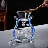 RORA magnetic glass teapot with loose tea leaves on a wooden scoop, dark backdrop