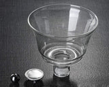 Glass tea funnel dripper with stainless steel ball filter and mesh component on a dark surface