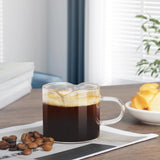 Small glass mug with two spouts filled with espresso, coffee beans on a wooden table